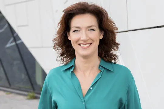 Ghislaine Plag met groen shirt. medium shot, buiten, met witte achterwand