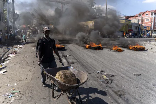 A man pushes a wheelbarrow near burning tires during a day of protest after the deaths of six police officers in Port-au-Prince, Haiti, January 27, 2023. US officials "condemn the gang violence that killed several Haitian National Police officers & call for calm amid ongoing protests," the assistant US secretary of state for Western Hemisphere Affairs, Brian Nichols, said on Twitter. Fourteen police officers have been killed by armed gangs since the beginning of the year, according to the National Union of 