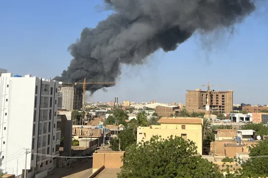A column of smoke rises behind buildings near the airport area in Khartoum on April 19, 2023, amid fighting between the army and paramilitaries following the collapse of a 24-hour truce. AFP