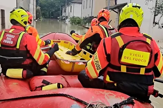 This photo taken and issued as a handout on May 17, 2023, by the Vigili del Fuoco, the Italian Corps of Firefighters, shows firefighters on a dinghy looking for potential people in distress in a flooded street in Faenza, Emilia-Romagna region. Heavy rains have caused major floodings in central Italy, where trains were stopped and schools were closed in many towns while people were asked to leave the ground floors of their homes and to avoid going out. The death toll rose to five on May 17, the Forli-Cesena 