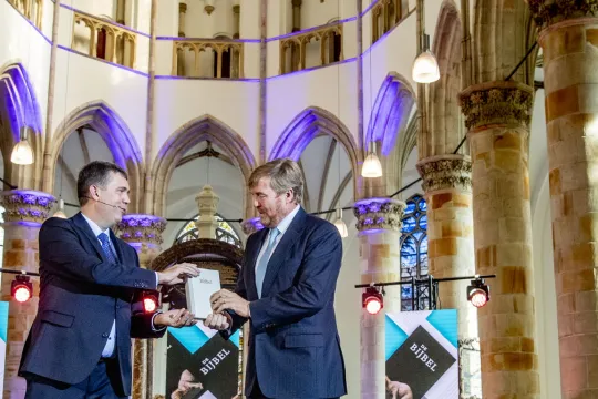 Koning Willem Alexander neemt in de Grote Kerk het eerste exemplaar van de NBV21, de vernieuwde Nieuwe Bijbelvertaling, in ontvangst. Koning Willem Alexander is beschermheer van het Nederlands-Vlaams Bijbelgenootschap. 