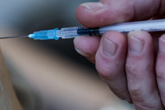 A resident of the Christalain nursing home in Brussels receives a dose of Pfizer-BioNTech Covid-19 vaccine on January 14, 2021 dispensed with a syringe and a needle that allow one extra dose of vaccine per vial. EU's medicines watchdog said on January 8, 2021 that six doses instead of five of the Pfizer-BioNTech coronavirus jab can be extracted from each vial if the correct needles are used, increasing the number of people who can be vaccinated with available supplies.