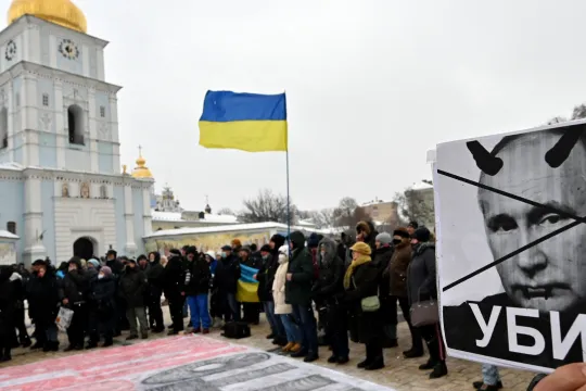 A demonstrator holds a placard depicting Russian president Vladimir Putin signed "Killer" during an action dubbed #SayNOtoPutin in Kyiv on January 9, 2022. 