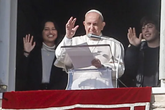  Pope Francis, flanked by two young people, waves from the window of his office overlooking Saint Peter's Square as he leads the recitation of the Angelus prayer, in Vatican City, 21 November 2021.