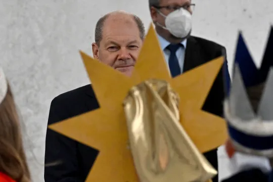 German Chancellor Olaf Scholz (C) listens to Epiphany singers (Sternsinger), groups of children who traditionally go from door to door dressed as the Three Biblical Magi offering carol blessings, as they sing outside of the Chancellery in Berlin, on January 5, 2022.