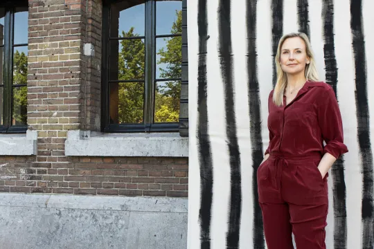 Blonde vrouw in rood pak staat voor zwart-wit-achtergrond