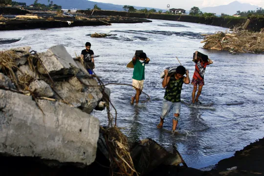 Villagers cross a river next to a damaged bridge in the aftermath of Tropical Storm Trami in the town of Laurel, Batangas province, Philippines, 27 October 2024. At least 82 people were killed and more than 250,000 villagers were forced to flee their homes as Tropical Storm Trami barreled in the Philippines, officials said on October 25. Trami dumped heavy rain, triggering widespread flooding and landslides. EPA/FRANCIS R. MALASIG