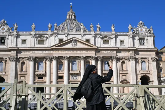 A nun takes photographs in front of the St. Peter's Basilica while the Pope is unavailable due to illness and will not lead the Angelus prayer at the Vatican on March 30, 2025. Andreas SOLARO / AFP