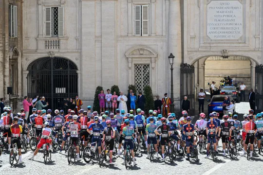 Pope Leo XIV (C) delivers a speech as he salutes riders, flanked by (From L) Lidl-Trek's Danish rider Mads Pedersen wearing the cyclamen jersey of best sprinter (Maglia Ciclamino), UAE Team Emirates XRG's Mexican rider Isaac Del Toro wearing the best young rider's white jersey (Maglia Bianca), Team Visma-Lease a Bike's British rider Simon Yates wearing the pink jersey of overall leader (Maglia Rosa), XDS Astana Team's Italian rider Lorenzo Fortunato wearing the best climber's blue jersey (Maglia Azzura) and