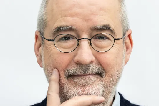 Man in zwarte trui voor witte muur