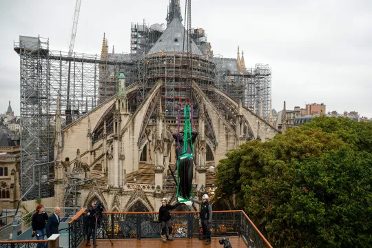 A crane lifts a statue of Saint-Thomas, the last one of the 16 giant copper-coated apostle statues, to be placed back atop the spire of Notre-Dame de Paris Cathedral in Paris on July 24, 2025. The statues, designed by Eugene Viollet-le-Duc and created by sculptor Adolphe Victor Geoffroy-Dechaume, had escaped the 2019 blaze at Notre-Dame, having been removed for renovation just days before the fire ravaged the cathedral. The statue bears the face of Eugene Viollet-le-Duc. GEOFFROY VAN DER HASSELT / AFP