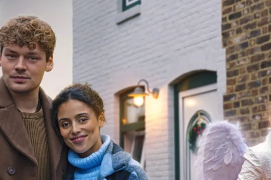 twee personen en een engel voor een rode auto