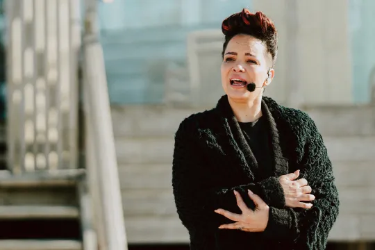 Vrouw staat voor een strandhuis te zingen