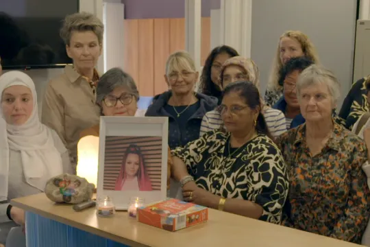 Groep vrouwen brandt een kaarsje bij een foto