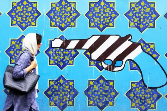 Vrouw loopt langs een muurschildering op de voormalige Amerikaanse ambassade in Teheran