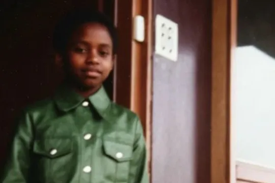 Meisje met groene jas in deuropening