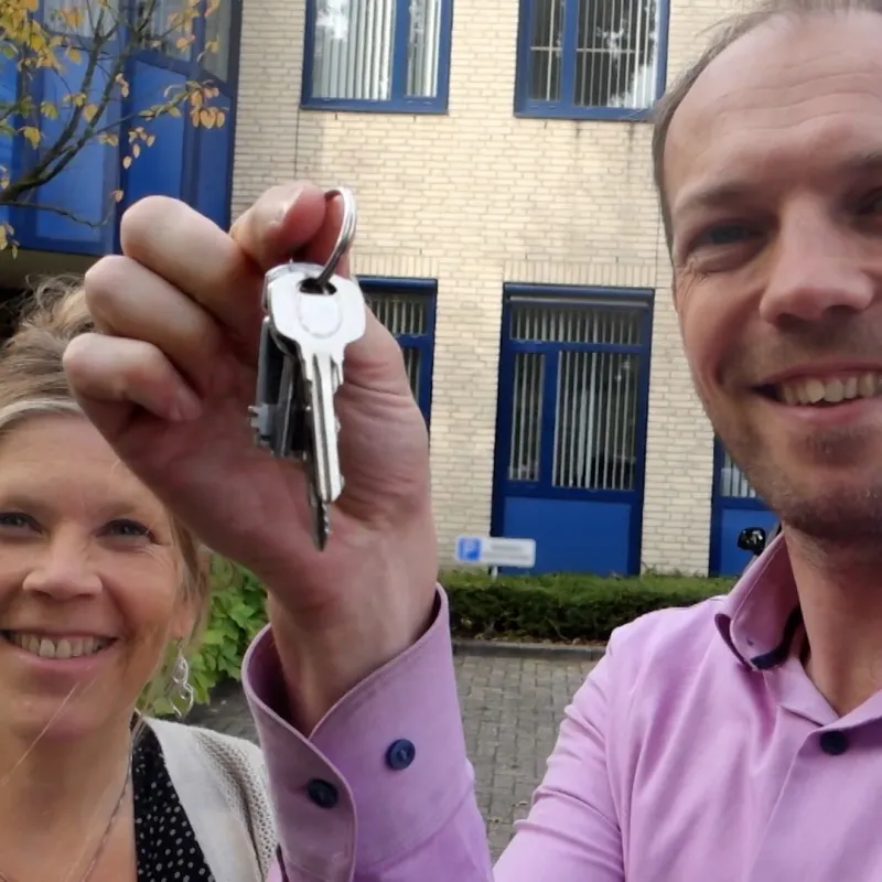 Man en vrouw blij met sleutel omhoog