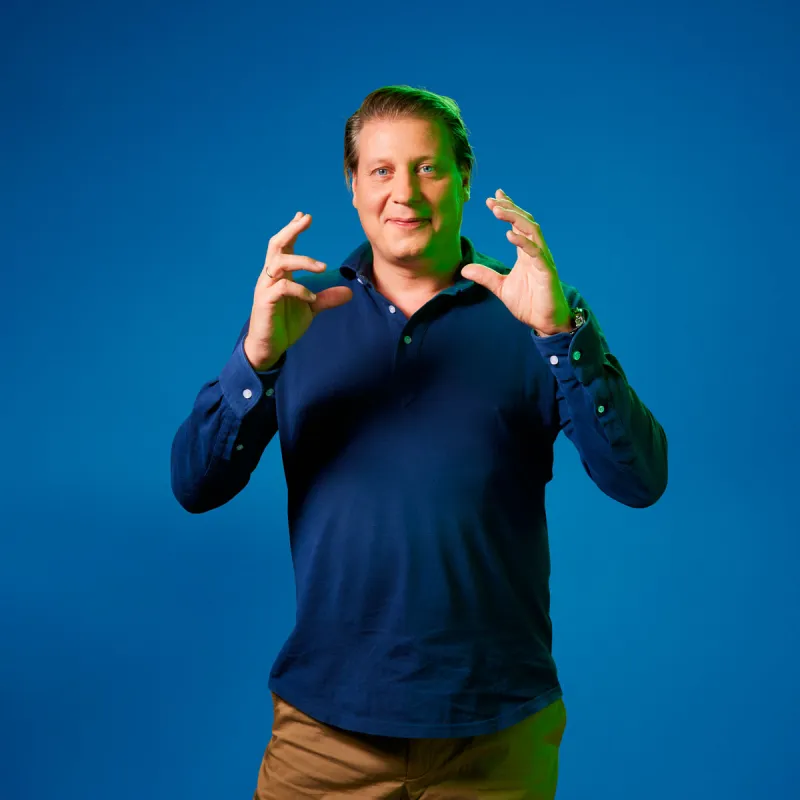 Leon Mazairac poseert voor een blauwe achtergrond in een blauwe trui