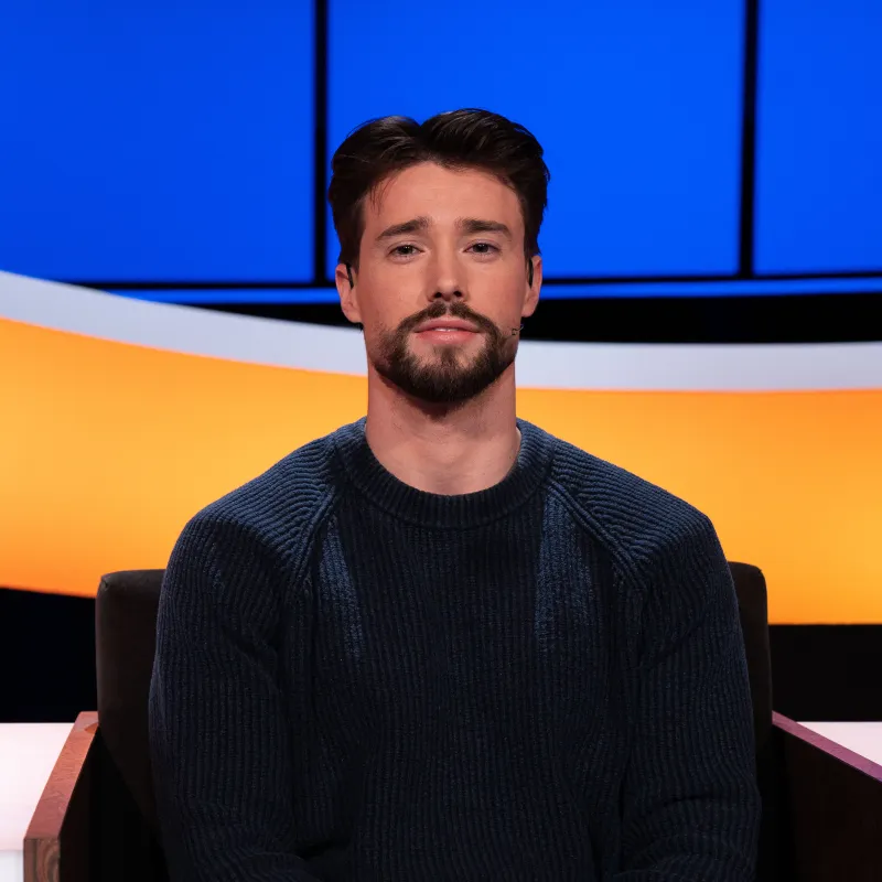 Jonge man met zwart haar en zwarte baard in donkerblauwe trui