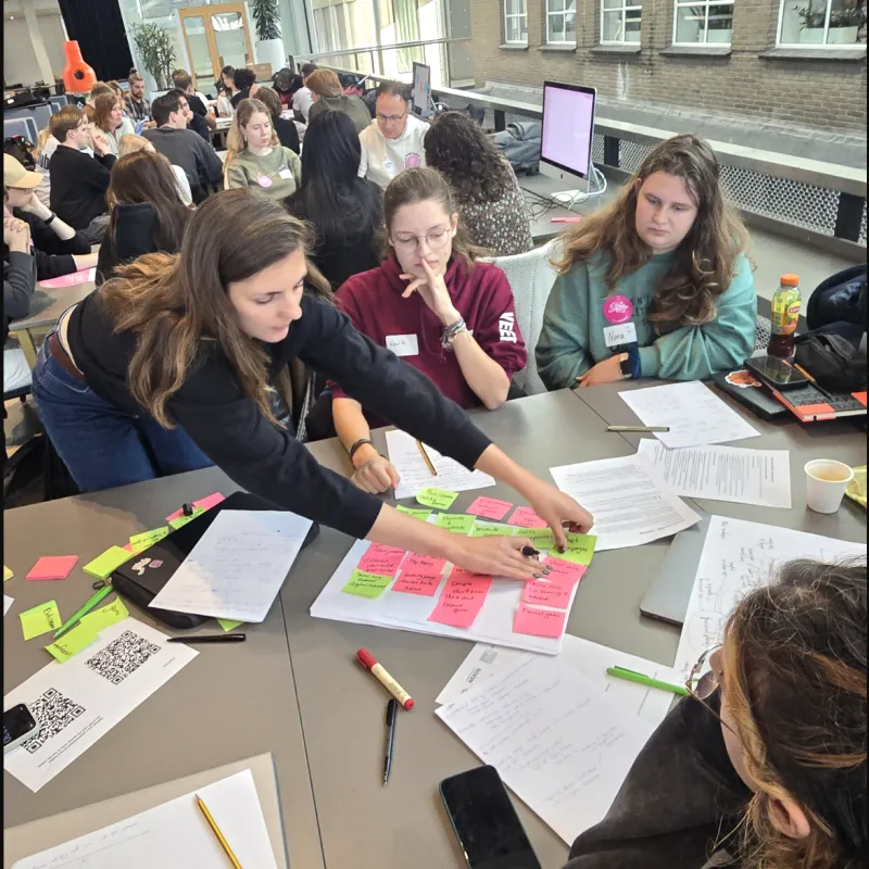Studenten tijdens brainstorm met post-its aan de slag in zaal