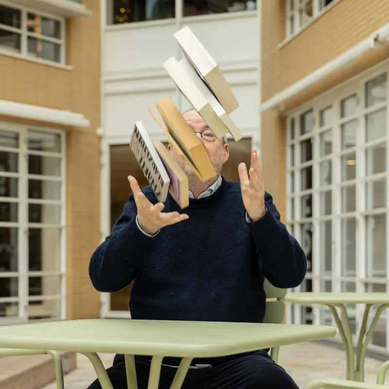 Man gooit een stapel met boeken de lucht in