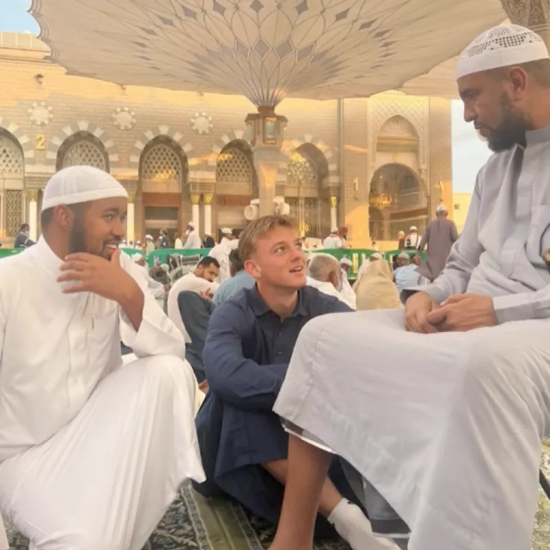 Jongen in blauwe doeken en mannen in witte doeken in moskee