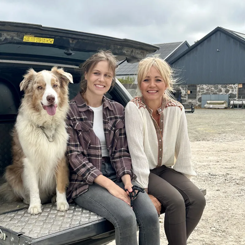 een hond en twee vrouwen zitten in de achterbak van een auto