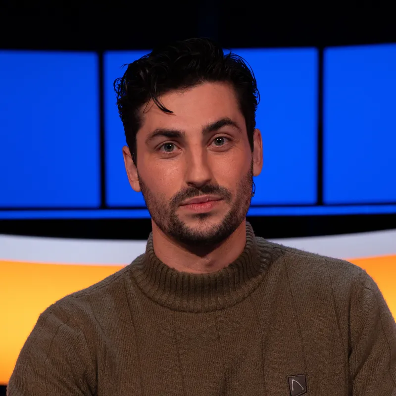 Man met zwart haar bruine coltrui 