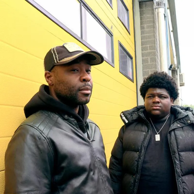 Twee mannen staan voor een gele garageklep