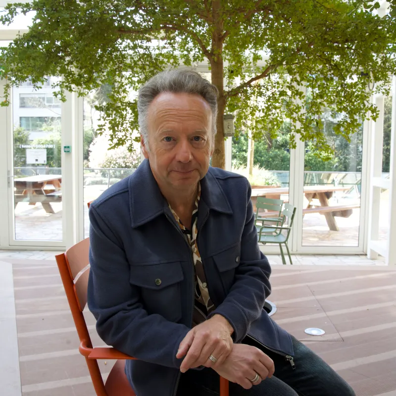 Man met grijs haar op een stoel onder een boom