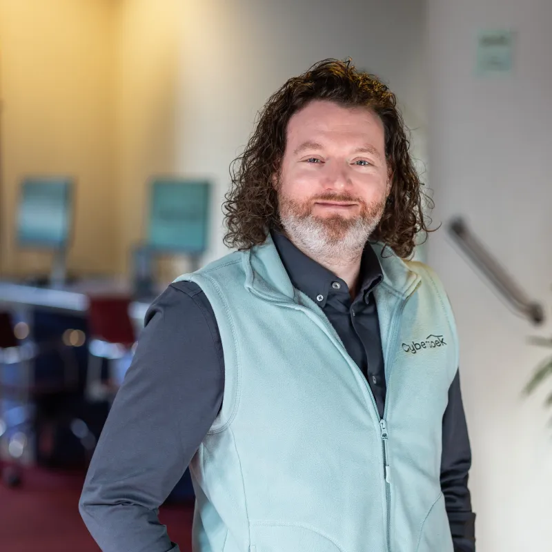 Man met lang haar staat met handen in zijn zakken en kijkt in de camera