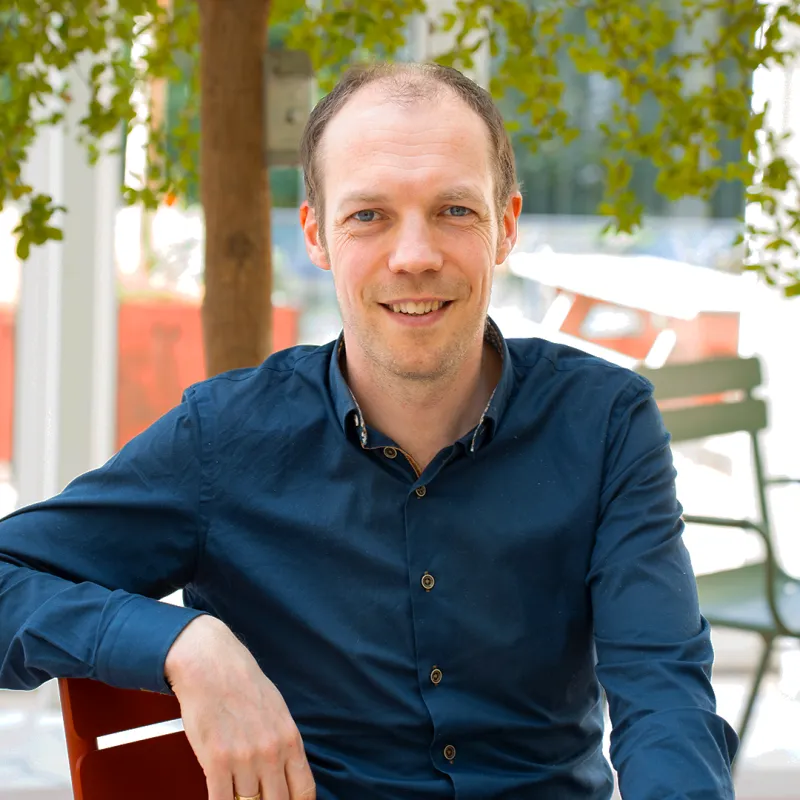 Meneer met blauw overhemd onder een boom