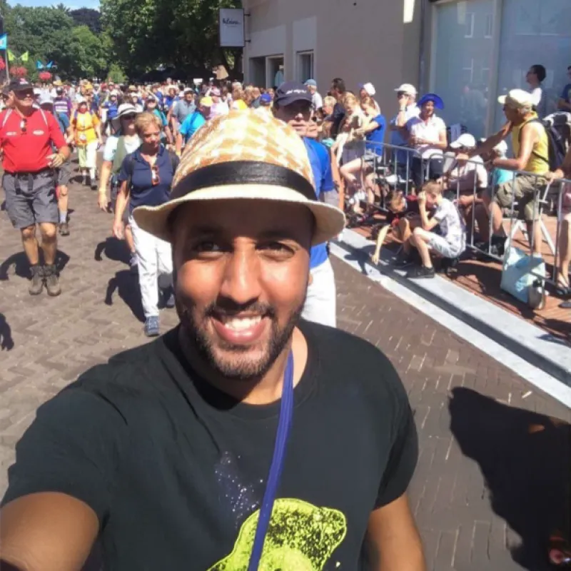 Mo Hersi loopt in de zon met een hoedje op tijdens de Vierdaagse