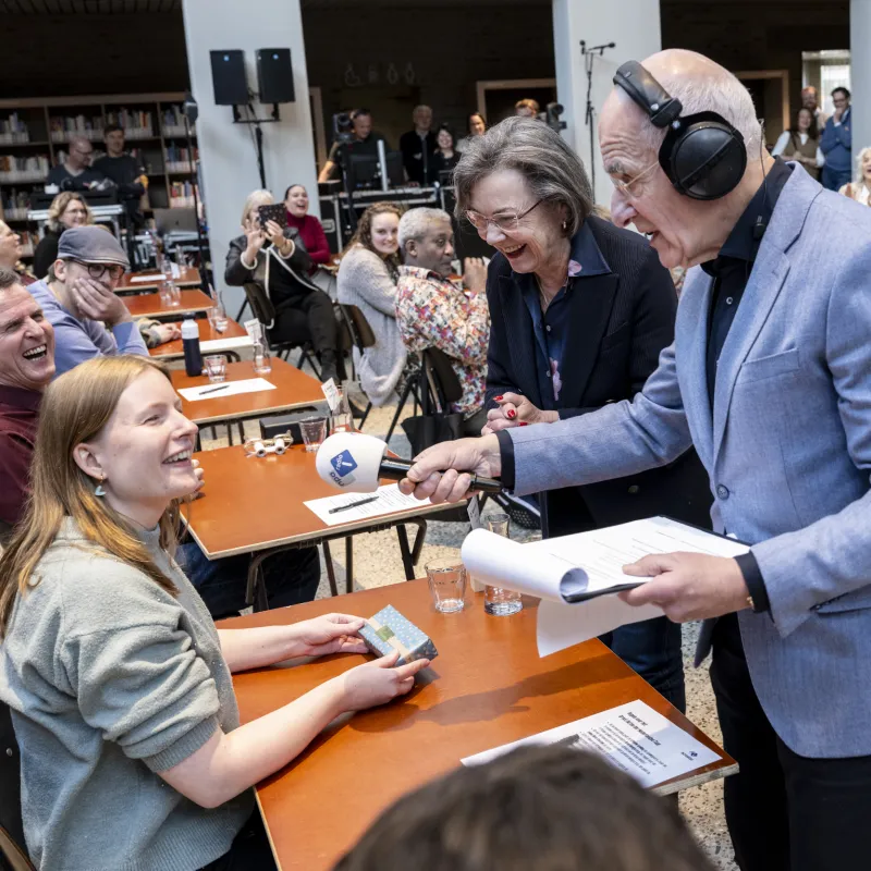 een man interviewt winnaar van een dictee