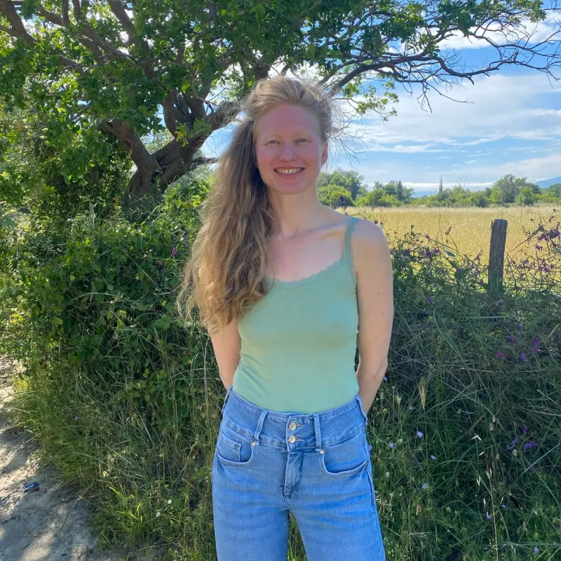 Vrouw met topje lachend voor heg