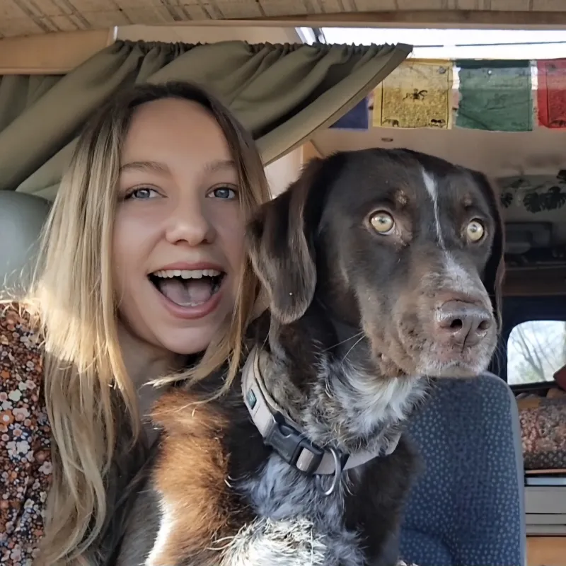 Vrouw met hond kijkt lachend de camera in