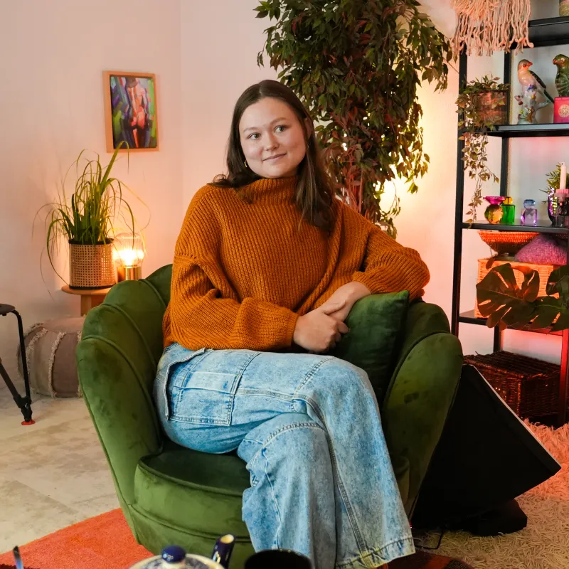 Vrouw poseert in stoel en kijkt naast de camera