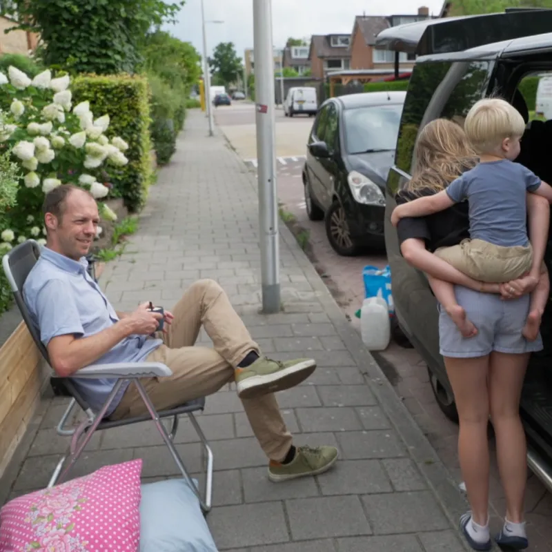 Man zit naast open bus met meisje met kind op rug