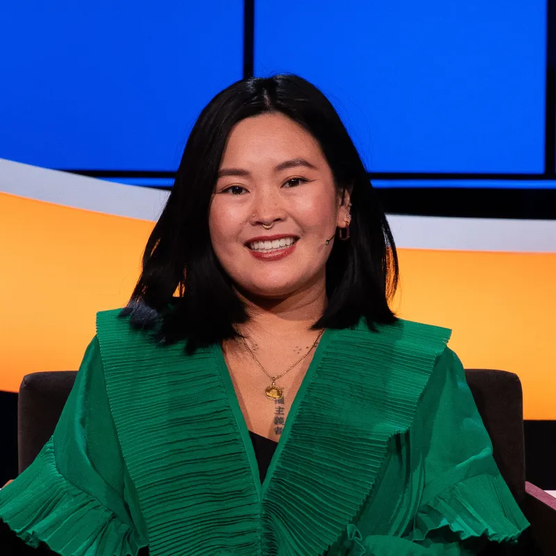 Lachende mevrouw met zwart haar en groene blouse