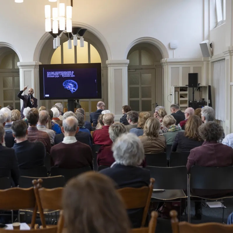 Publiek luisteren naar spreker in zaal