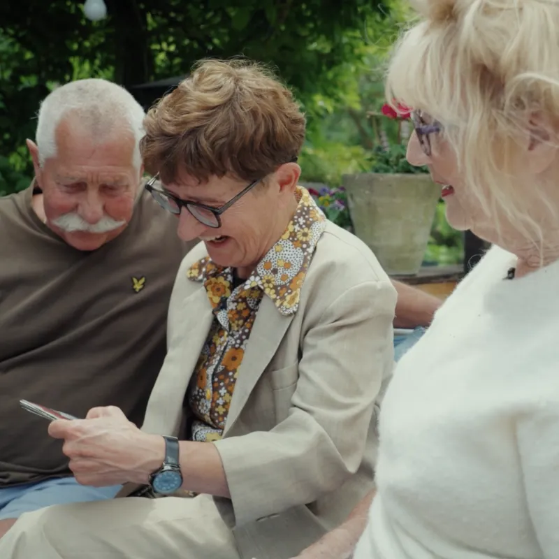 Drie personen op een bankje in de tuin