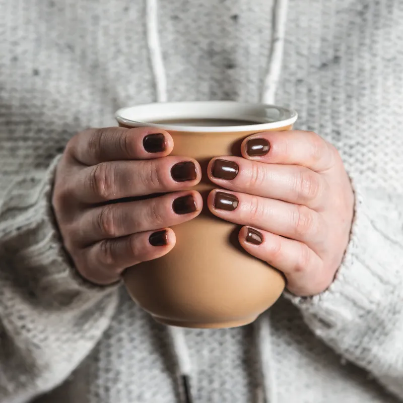 Twee handen houden een kop thee vast