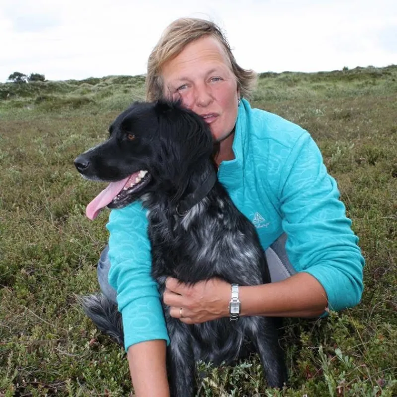Een vrouw met haar hond tussen de duinen