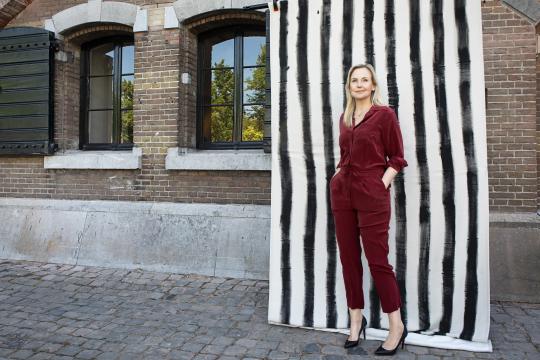 Blonde vrouw in rood pak staat voor zwart-wit-achtergrond