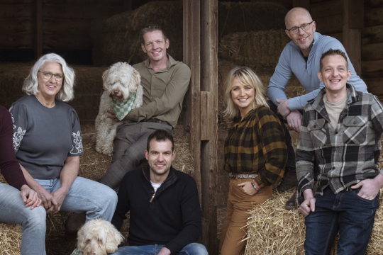 een groep mensen poseert in een stro-opslag