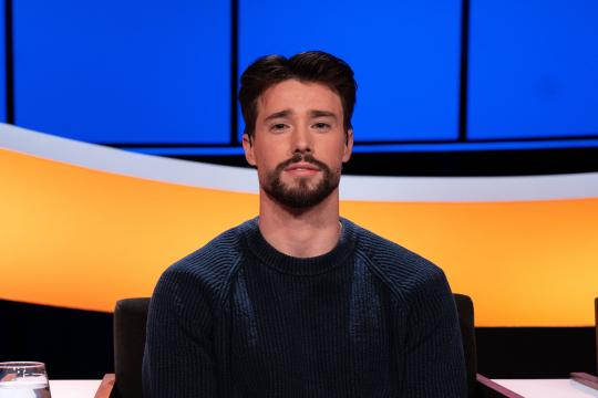 Jonge man met zwart haar en zwarte baard in donkerblauwe trui