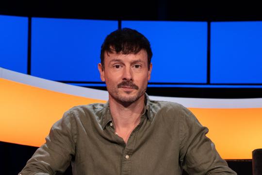 Man met donker haar en snor en groen overhemd