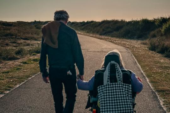 Vrouw in rolstoel met man naast haar in natuur