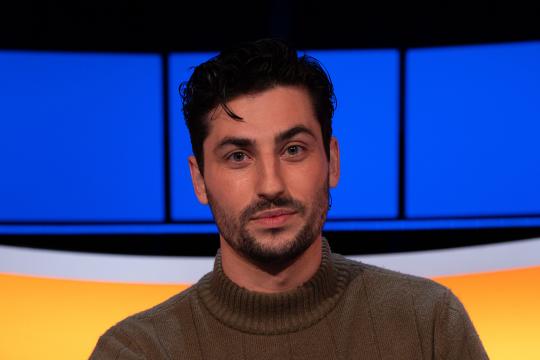 Man met zwart haar bruine coltrui 