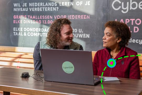 Twee mensen achter een laptop kijken elkaar aan
